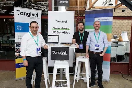 A group of three people at a sponsor stand pose for a photo.