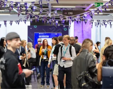 Attendees gathered under bunting that reads: UX London.