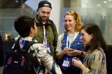 A group of people gathered in a circle smiling and chatting to one another.